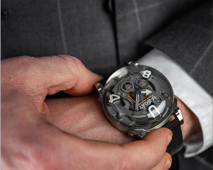 Person wearing a suit with a close-up of a mechanical U-BOAT watch on the wrist.